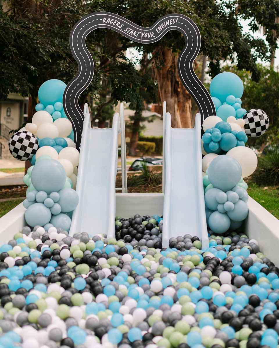 Race-car ball pit with twin slides, blue balloons and black-and-white checkered accents