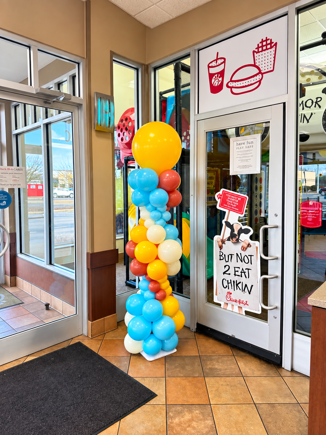 A sky blue, yellow, cream and terracotta balloon column at a restaurant entrance