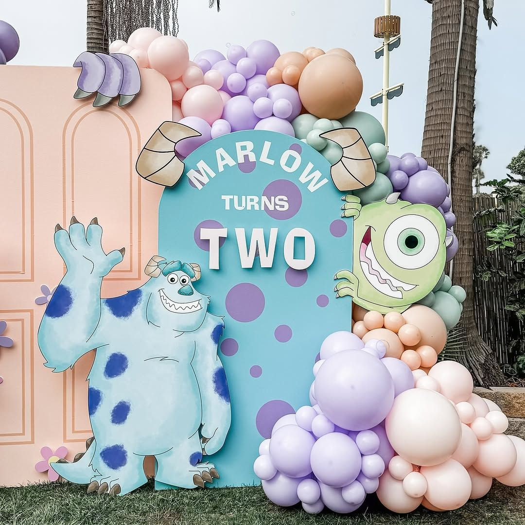Pastel peach, lavender and mint Monsters-inspired birthday backdrop with sculptural balloons