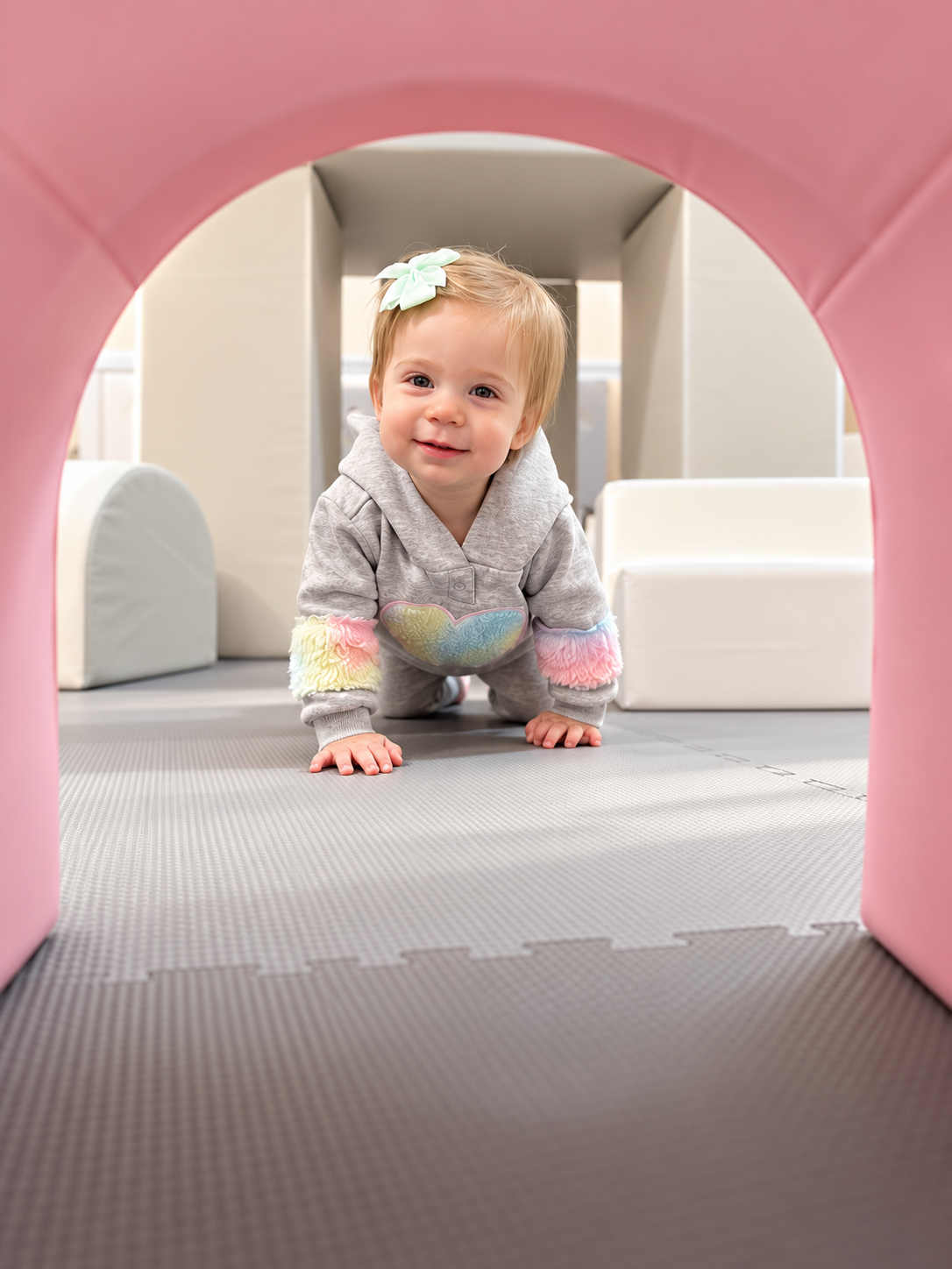 Toddler crawling through a pink arch in a Classic play space