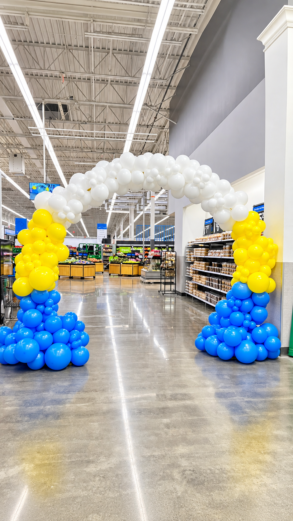 A white, yellow and blue balloon arch styled inside a big-box store aisle for a corporate brand event