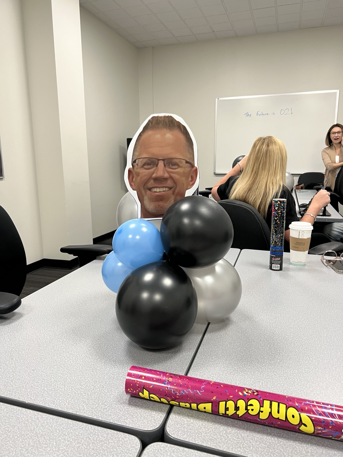 A blue, black and silver balloon cluster centerpiece on an office conference table